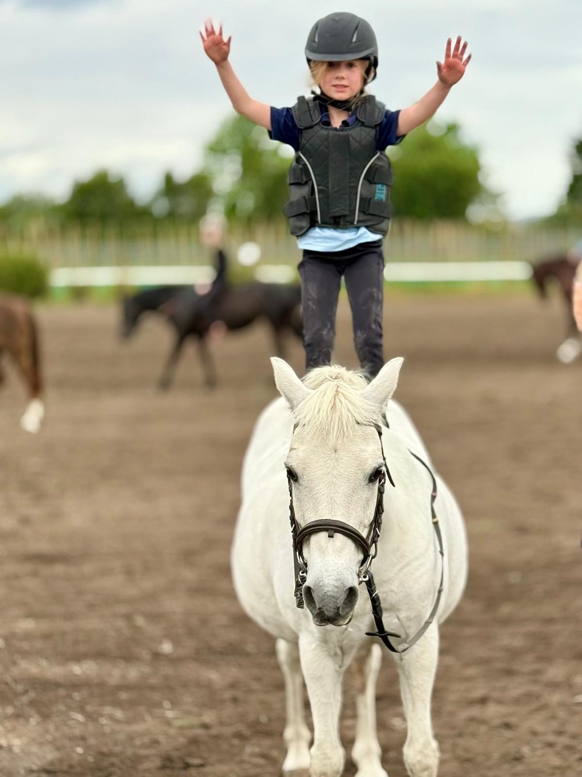 A young rider standing on her pony in the arena at Acreswild