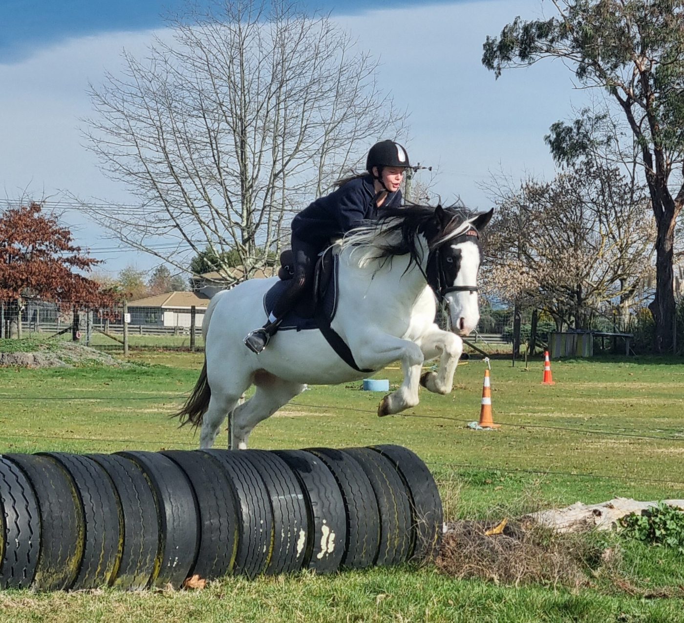 A rider jumping her pony over the tyres at Acreswild
